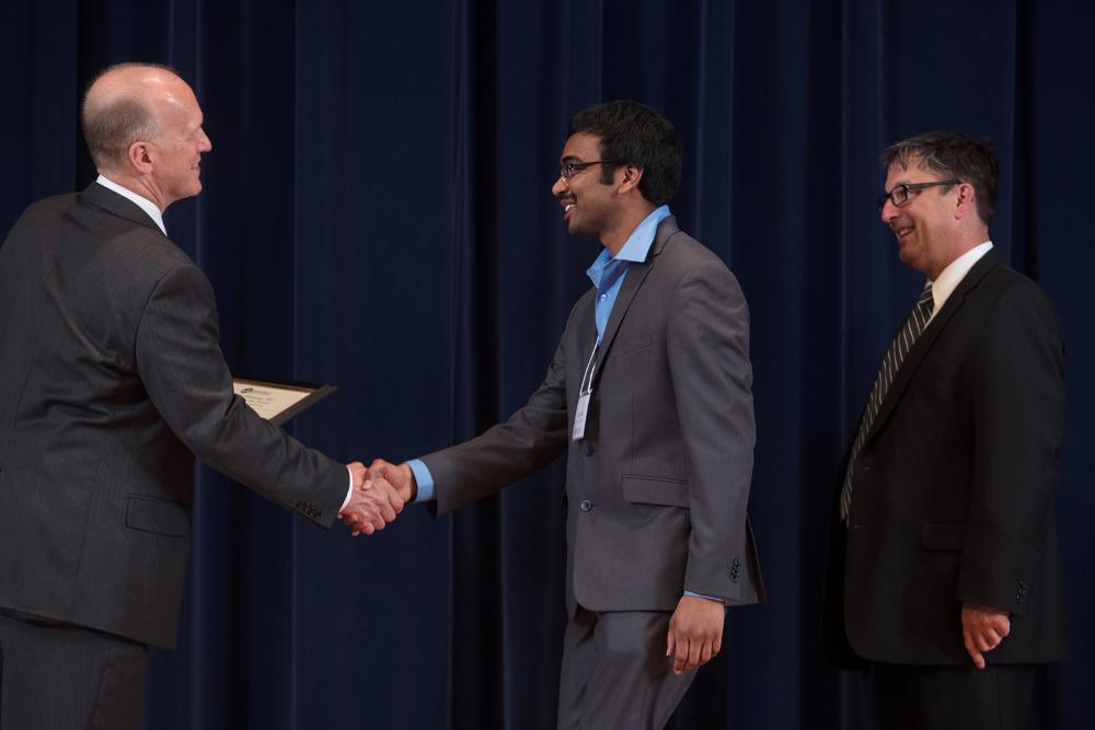 Doctor Potteiger shaking hands with an award recipient in a grey suit